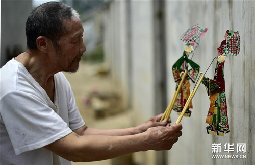 6月5日,張奎老人在屋外的墻上耍皮影(岳月偉