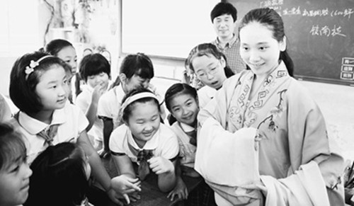 5月31日,浙江省新昌縣調(diào)腔劇團演員曹曉云(右一)為南巖小學學生講解新昌調(diào)腔的戲服特點。(新華社記者劉勇貞