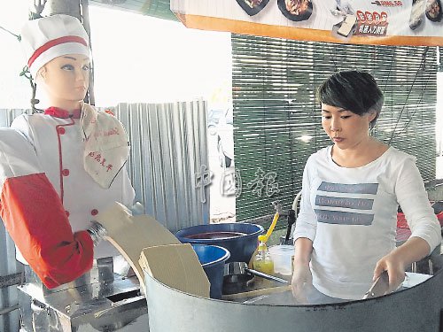 機器人站在爐子旁削面,王麗萍撈起烹煮。(馬來西亞《中國報》/張書樂