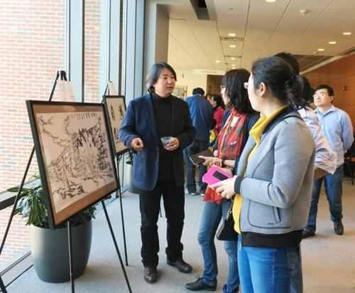 中國(guó)僑網(wǎng)燕昱向觀展者介紹畫作。(美國(guó)《僑報(bào)》/郁婕 攝)