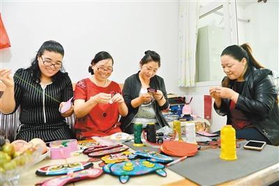 中國(guó)僑網(wǎng)武麥花(中)與繡娘一起繡制虎頭眼罩。 楊力 攝