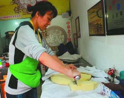中國僑網(wǎng)薛福泉的愛人林穎正在切黃米糕。