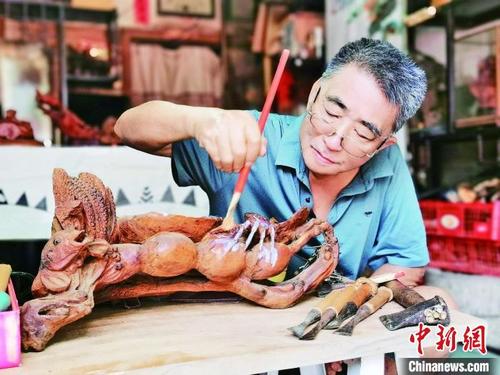 中國(guó)僑網(wǎng)廣州增城根雕非遺傳承人吳金石在創(chuàng)作中 增城區(qū)委宣傳部 供圖